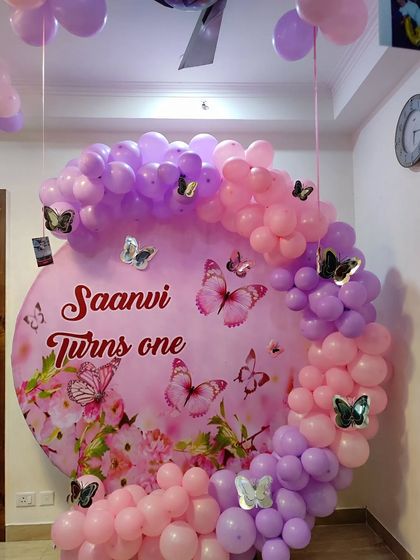 A beautiful butterfly theme for Saanvi's first birthday. The custom backdrop is surrounded by a pink and purple balloon arch with delicate butterfly details.