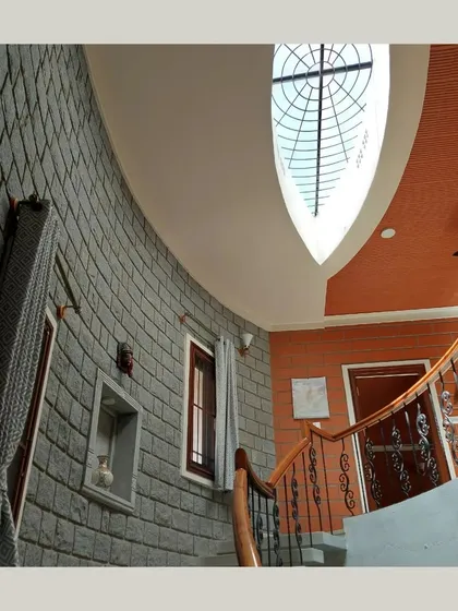 A dramatic, low-angle view of a curved stone wall ascending towards a unique, eye-shaped skylight.