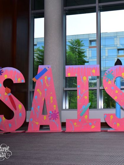 Giant, personalized letters spelling out the birthday girl's name, 'SAISHA', decorated with a paint splatter effect.