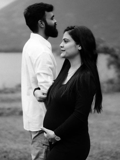 A classic black and white portrait of the couple by the water. The way they are looking at each other captures a moment of deep and quiet connection.