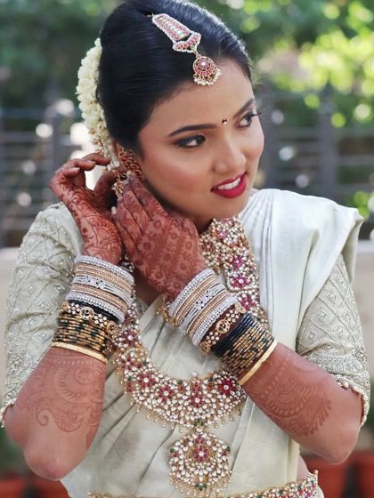 Kavya looks absolutely gorgeous in her muhurtham makeover. This candid shot captures her getting ready, with her flawless makeup, intricate henna, and stunning temple jewellery on full display.