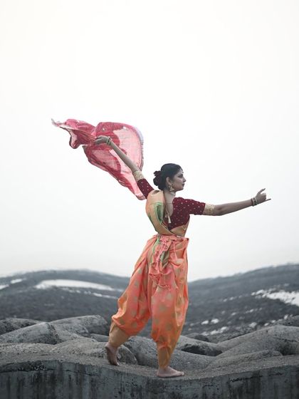 A powerful pose embodying the energy of Maa Shakti. The dramatic landscape and flowing costume create an image of strength and divine feminine power.