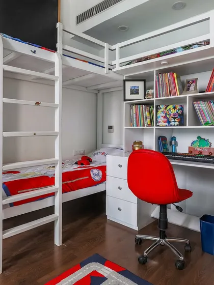 A highly functional kid's room with a white bunk bed that has an integrated bookshelf and study desk, making the most of a compact space.