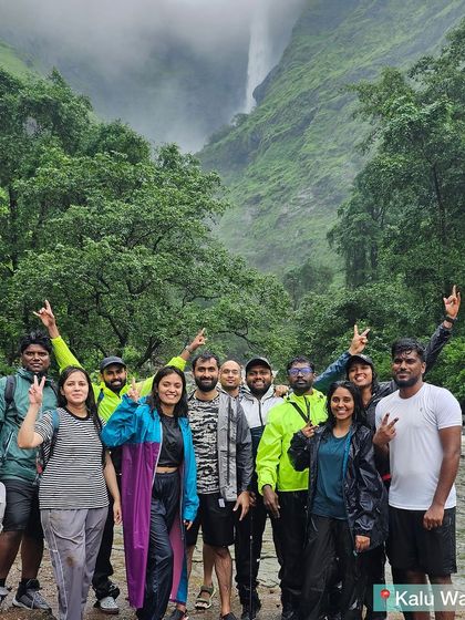The trekking team posing in their rain gear with the majestic Kalu waterfall shrouded in mist behind them.