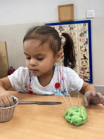 A child uses toothpicks with playdough, a simple yet effective way to practice a pincer grasp and develop hand-eye coordination. The sensory feedback from the dough makes the fine motor practice more engaging.