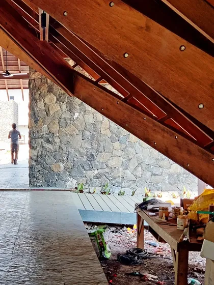 A view from under the deep eaves of the Alibaug residence. The design creates a series of transitional spaces that are neither fully inside nor out, encouraging a fluid connection with the surrounding environment.