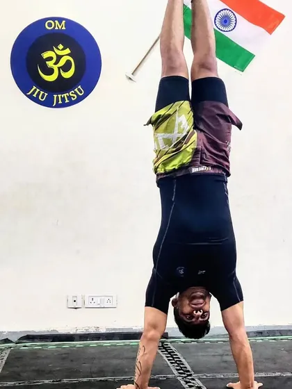 Strength is not just about fighting; it's about balance and control. We integrate practices like yoga and calisthenics, seen here with a handstand, to build core strength, flexibility, and mental focus for complete functional fitness.