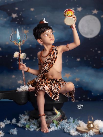 A powerful pose from a young boy as Lord Shiva, looking up at his damaru against a starry night sky.