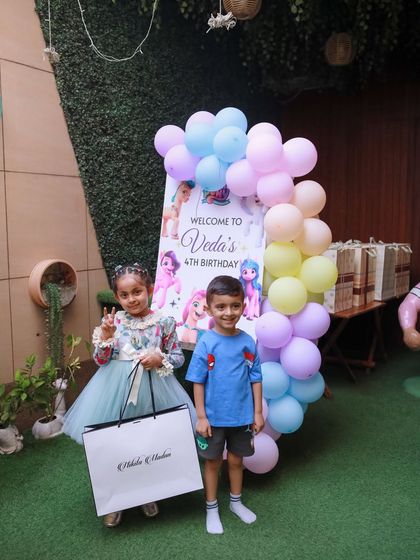 The birthday girl greets her guests at the entrance, standing by her personalized "My Little Pony" welcome sign.