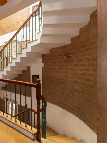 The curved wall of the staircase, clad in earth blocks, showcases the versatility of the material and adds a soft, organic line to the interior.