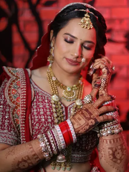 Adjusting the nath is a classic bridal pose. Her makeup, with its warm tones and subtle shimmer, is designed to highlight her features without overpowering her intricate jewelry.