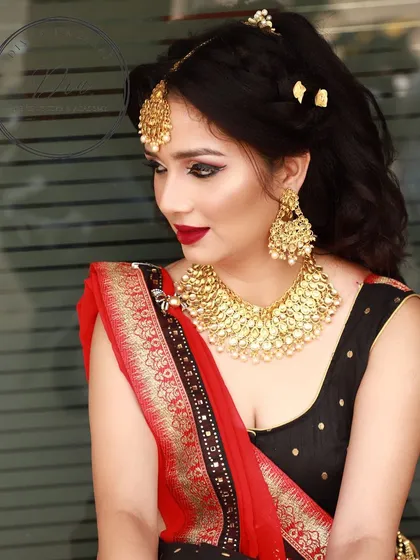 A classic combination of a red lip and defined eyes, but with a soft touch. The makeup enhances her features beautifully, paired with a traditional saree and heavy gold jewellery.