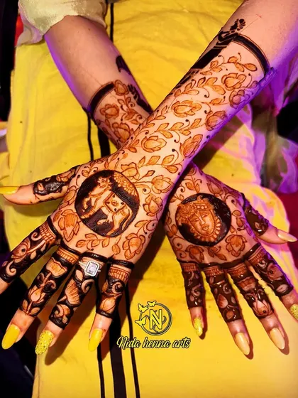 The client showing off her beautiful back hand design with traditional figures against a festive yellow background.