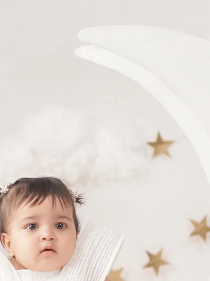 A close-up detail from a 'Moon & Stars' shoot, focusing on the baby girl's curious expression and cute pigtails.