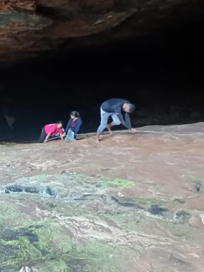 Trekkers carefully making their way down a slippery rock surface.