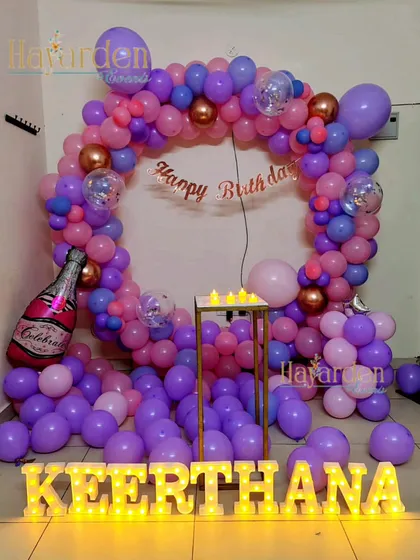 A fun and colorful balloon ring in shades of purple and pink. The scattered balloons on the floor and marquee letters complete this lively home party setup.
