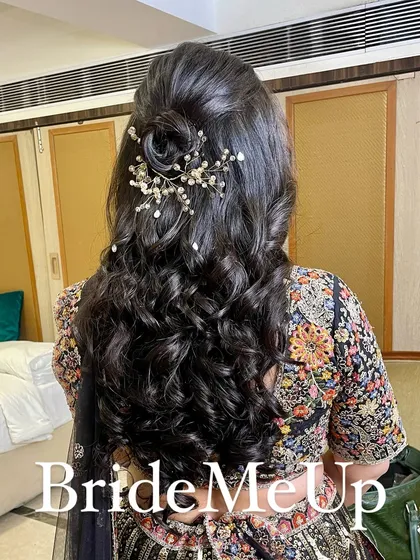 A view of the elegant half-up, half-down hairstyle with a rose-shaped bun and pearl accessories, perfect for a reception.