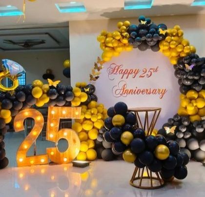 A grand 25th anniversary celebration in black and gold. This large setup includes balloon columns, a themed arch, and light-up numbers, creating an impressive display.