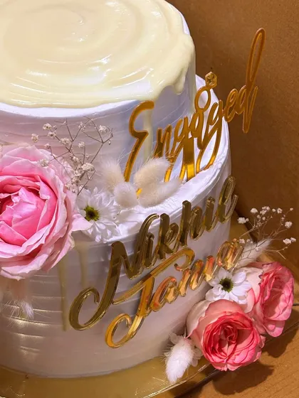 A detailed shot of the engagement cake's floral arrangement, featuring pink roses and dried botanicals.