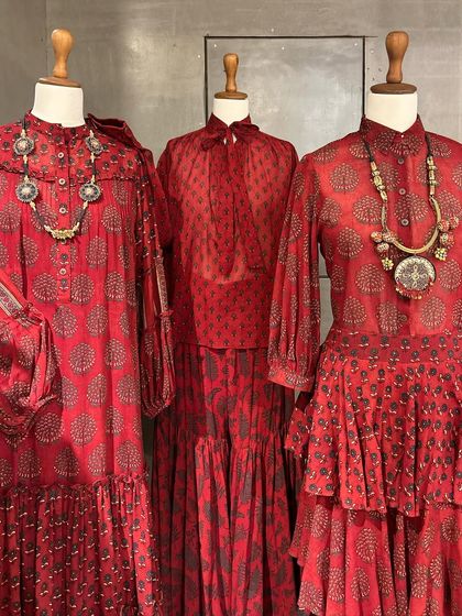 A collection of beautiful red block-printed dresses and tops, styled with chunky tribal necklaces for a bohemian-chic vibe.