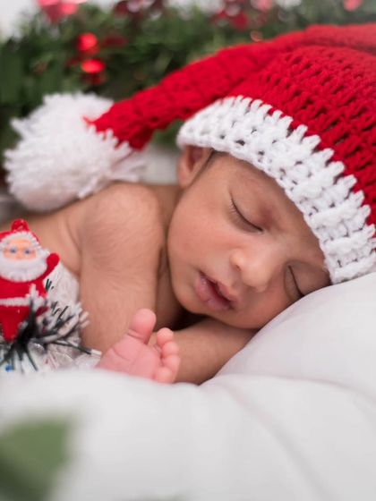 Getting into the festive spirit with a tiny Santa. This Christmas themed newborn photo uses a cute knitted hat and subtle holiday props to create a memorable first Christmas portrait.