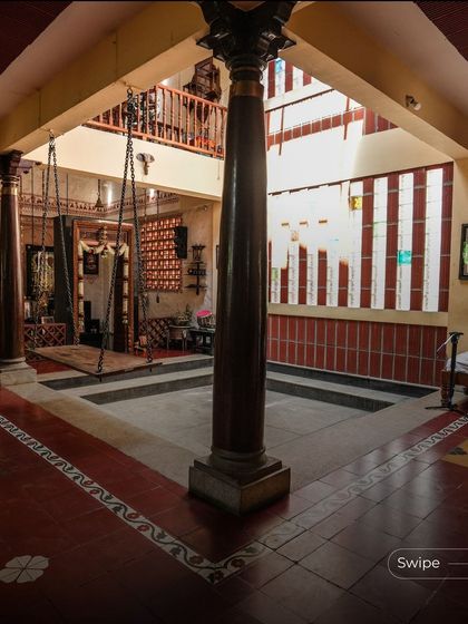 The stunning central courtyard of the Padmaja Rao Residence, complete with traditional wooden pillars, a swing, and an open skylight, creating a classic and serene heart of the home.
