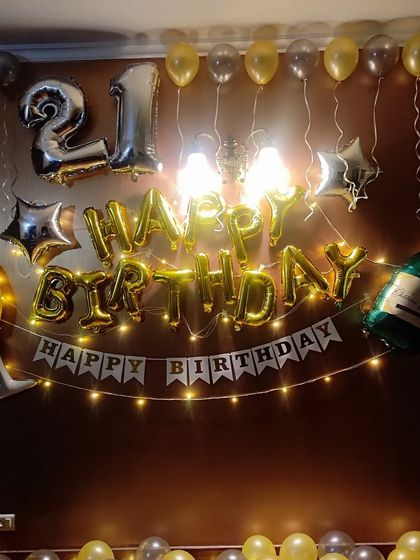 A 21st birthday home decoration with gold and silver balloons, "Happy Birthday" banner, and champagne foil balloons.