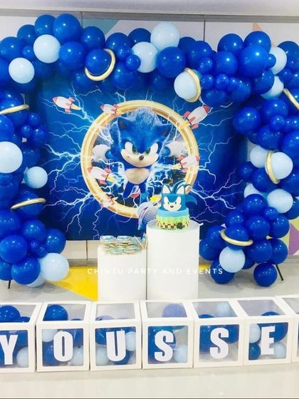 A Sonic the Hedgehog themed birthday party. The decoration includes a blue balloon arch framing a dynamic backdrop and personalized name blocks.
