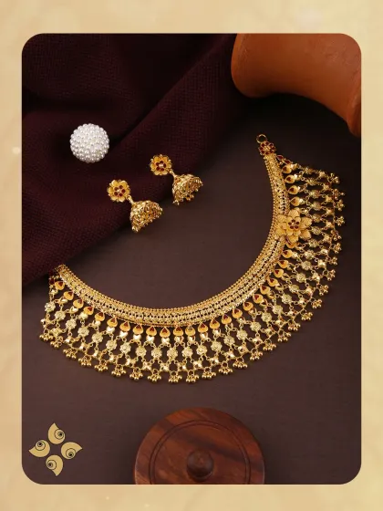 Statement-making in every sense. This gold choker set features a traditional design with intricate detailing and matching jhumkis, crafted to stand out in your collection.