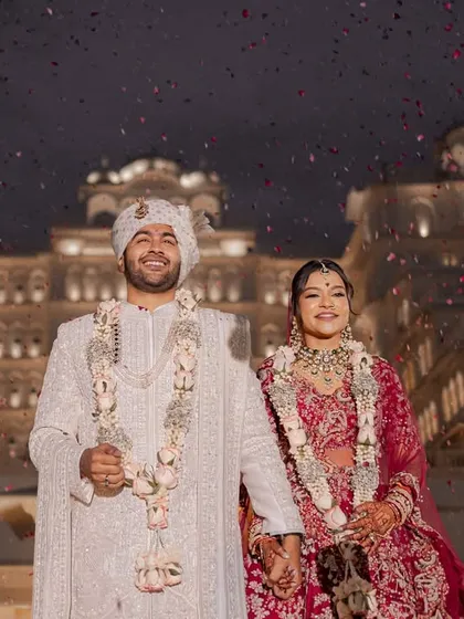 As confetti rains down against the backdrop of an illuminated palace, the couple shares their first moments as husband and wife. This is the kind of fairytale ending that marks a beautiful beginning, a memory of pure joy from a destination wedding in Jaipur.