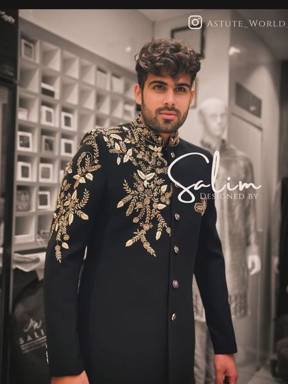 A client wearing a black Jodhpuri jacket with gold floral embroidery on the shoulder and collar. This is a classic design that is both timeless and elegant.