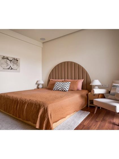 In this bedroom, we designed a custom arched, channel tufted headboard and a minimalist wooden armchair. The space is a fusion of rustic and elegant styles, using honest materials to create a peaceful haven.