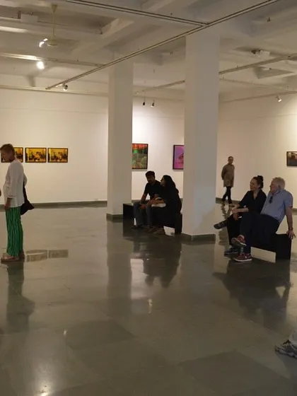 A view of the gallery space with visitors seated and observing the art.