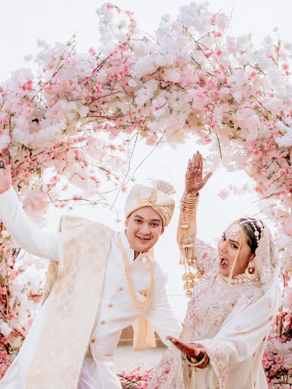 A fun and playful portrait of the couple under a cherry blossom arch. Their energetic poses and happy faces show the fun side of their relationship.