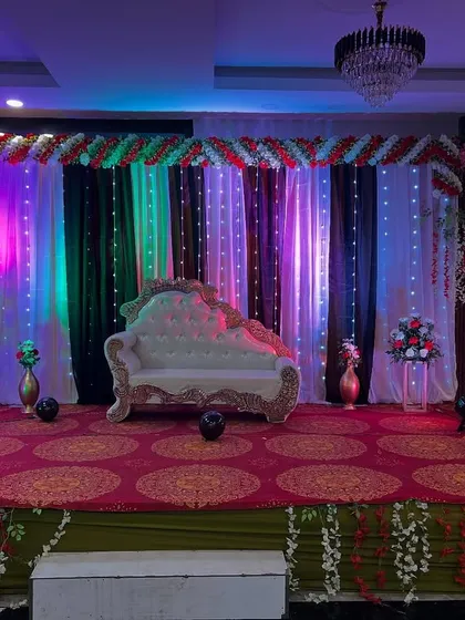 A versatile stage setup with a multi-color lighting scheme, a classic diwan, and a fairy light curtain backdrop, suitable for various events like sangeets or receptions.