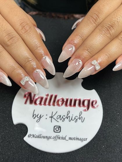 A beautiful 9D cat-eye effect on stiletto nails, giving a pearlescent, multi-dimensional look, finished with delicate rhinestone bows.