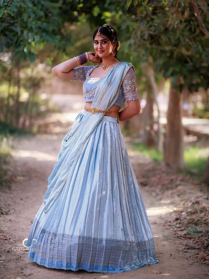 A full-length portrait on a rustic path. The natural surroundings complement the soft blue of her lehenga, creating a fairytale-like image.