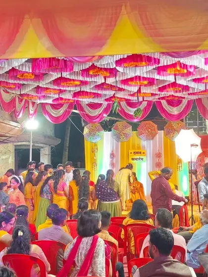 A wide shot of a lively Haldi ceremony. You can see the crowd enjoying the function under a ceiling decorated with pink and yellow fabric, with my DJ setup ready to keep the party going.