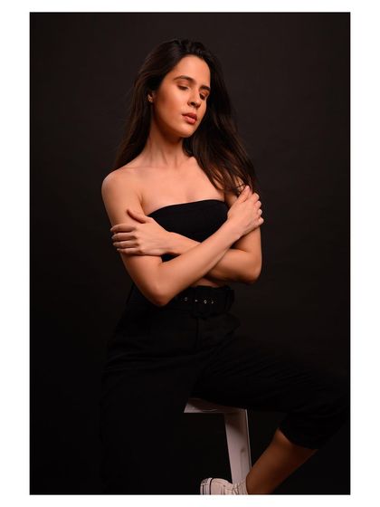 A minimalist and modern fashion portrait. The simple black outfit and dark background create a sleek and sophisticated look.