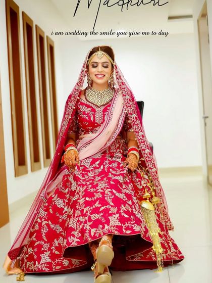A full-length portrait of the beautiful bride Madhuri, seated and smiling. Her stunning red lehenga and radiant happiness are the centerpiece of this classic bridal shot.