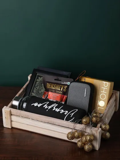 A great example of a personalized luxury hamper, this wooden tray includes a custom-named bottle, a portable speaker, Hershey's chocolate, and Phool incense cones.