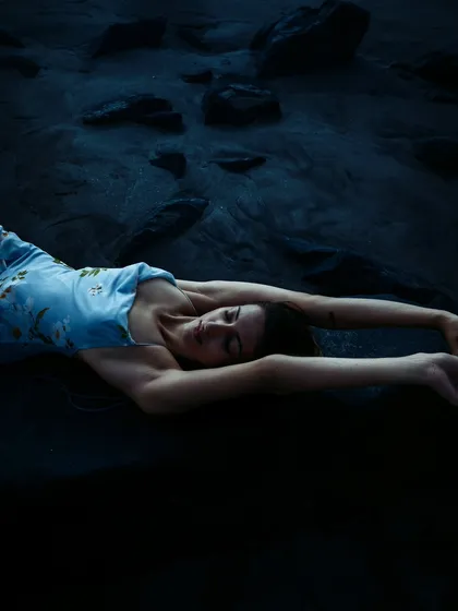 Another artistic composition from the blue-hour shoot, with the model lying on the dark sand. The image feels quiet, vast, and deeply calming.