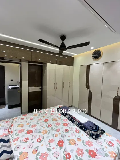 A wider view of the bedroom, showing the large wardrobe and the bed. The profile lights in the false ceiling provide soft, ambient illumination.