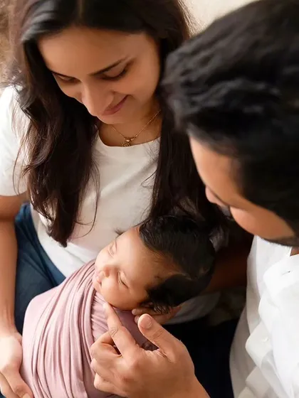 A quiet, intimate moment with parents gazing at their swaddled newborn. These lifestyle shots capture the overwhelming love and connection in a new family.