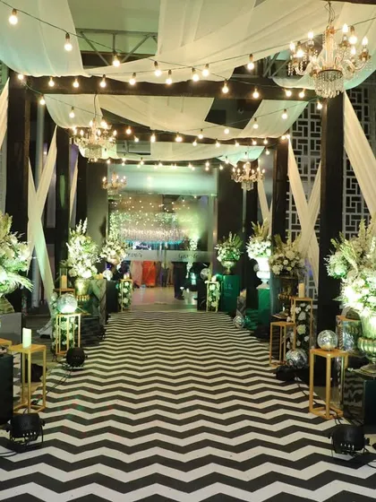 For a glamorous cocktail night, I designed this entrance with a bold chevron-patterned floor, white drapes, and sparkling disco balls, setting the stage for a fun-filled party.