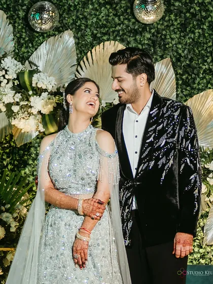 A happy, candid shot of the couple at their engagement, sharing a laugh against a lush green backdrop.