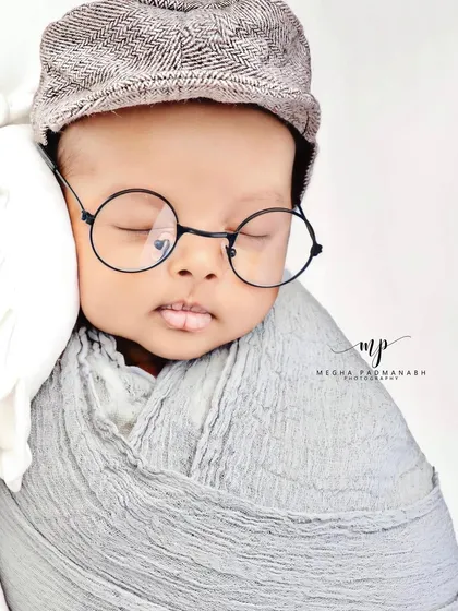 A close-up portrait of the baby with the cap and glasses.