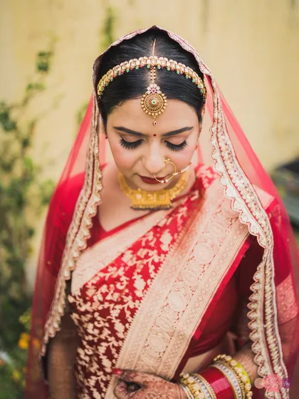 A moment of quiet reflection for the bride, Aditi, in her beautiful red Banarasi saree. Her traditional jewelry and serene expression are timeless.