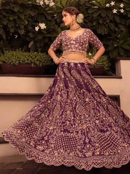 A full-length shot of the purple "Noor" lehenga. The rich color and heavy gold embroidery create a look of pure royalty.