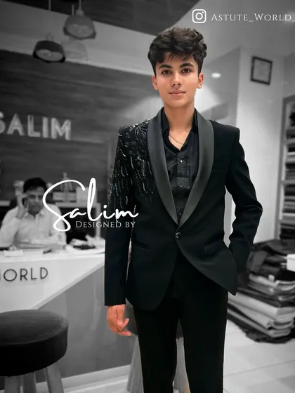 A young client in a black tuxedo with an embellished shoulder piece. It's a modern, asymmetrical design that's perfect for a stylish young man.